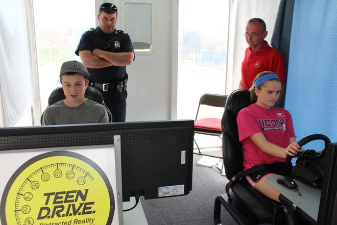 Auburn Police School Resource Officer Brian C. Kennedy and Teen DRIVE program instructor Leo Perreault watch as Auburn High School drivers Colleen Cutting and Kyle Montville experience virtual impaired and distracted driving.