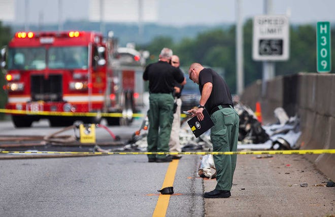 Investigators look at the wreckage of a plane that crashed on Interstate 285, Friday, May 8, 2015, in Doraville, Ga. A small passenger airplane crashed into an Atlanta interstate Friday, killing all four people aboard and starting an intense fire on the busy road, authorities said. (AP Photo/David Goldman)