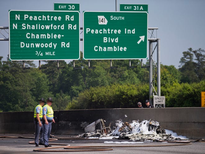 Police look toward the wreckage of a plane crash on Interstate 285, Friday, May 8, 2015, in Doraville, Ga.
