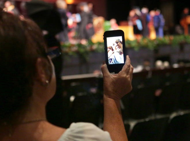 Lesley Perdue holds up her phone so that her mother, Janie Maples, whom she says is terminally ill, can watch her daughter and Lesley’s sister, Cindy Lockwood, receive her bachelor's degree through a FaceTime video call during the Florida State University Panama City commencement ceremony Sunday. “All she ever wanted was for one of us to graduate college,” Perdue said.