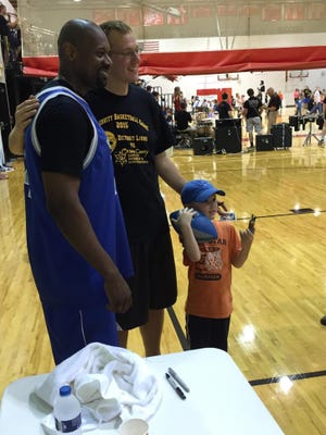 Former Detroit Lions wide receiver Herman Moore, left, takes a photo with Holland resident Scott Steenwyk, center, and his son Brian, 5, during a charity basketball game at Allendale High School on Saturday, May 9. Contributed/Lee Lamberts