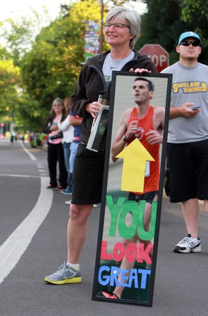 Linda Silva of Eugene watches as runners in the Eugene Marathon last year pass by her custom-made mirror at Hayward Field. This year's event is Sunday, and there are ample opportunities for fans to cheer on the runners along the race route. (Alan Sylvestre/The Register-Guard)