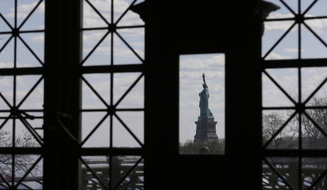 Windows on the south side of the Great Hall at Ellis Island frame the Statue of Liberty, in New York. With the unveiling of a new exhibition next month, Ellis Island is telling stories of immigrants who have come as recently as the start of this century. AP Photo/Julie Jacobson