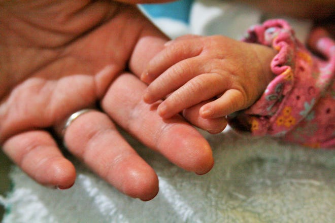 Mavis Harned puts her hand on top of that of her mother, Tui, while being fed in the neonatal intensive care unit at Rockford Memorial Hospital on Tuesday, May 5, 2015. MAGGIE HRADECKY/RRSTAR.COM