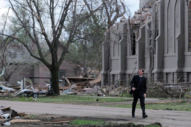 The REV. DAVID OTTEN, from Immanuel Lutheran Church in Dimock, S.D., walks down Main Street in Delmont, S.D., in front of Zion Lutheran Church after a tornado tore through the area, damaging homes and businesses on Sunday morning. Later Sunday and early Monday a line of tornadoes battered communities in Texas and Arkansas.