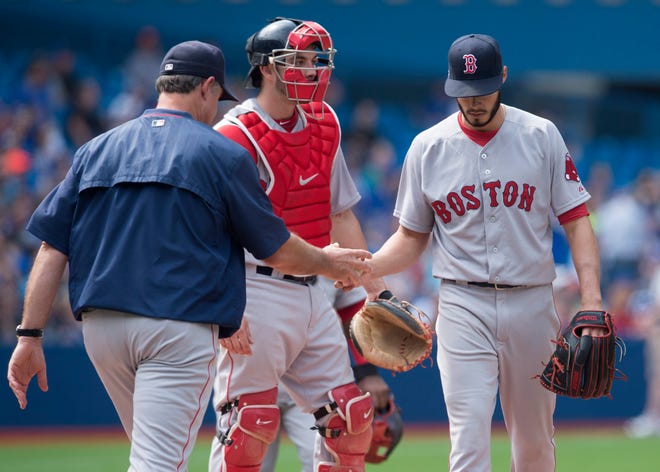 Boston Red Sox starting pitcher Joe Kelly, right, hands the ball to manager John Farrell, left, before leaving a game against the Toronto Blue Jays in Toronto on Saturday. Photo by AP