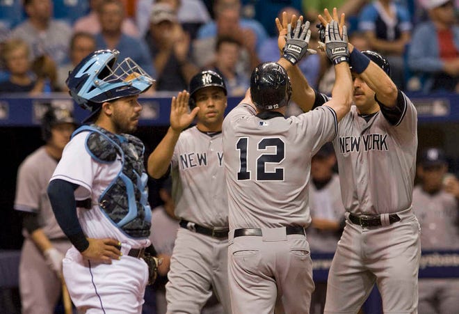 Tampa Bay Rays catcher Rene Rivera, left, stands to the side as New York Yankees' Carlos Beltran, Chase Headley (12) and Mark Teixeira, right, celebrate Headley's three-run homer off Tampa Bay starter Alex Colome during the fourth inning of a baseball game Monday, May 11, 2015, in St. Petersburg, Fla. (AP Photo/Steve Nesius)