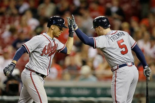 Atlanta Braves shortstop Andrelton Simmons, left, celebrates his solo home run with first baseman Freddie Freeman during the fourth inning of a baseball game against the Cincinnati Reds, Monday, May 11, 2015, in Cincinnati. (AP Photo/John Minchillo)