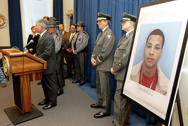 U.S. Arrorney Greg White, at podium, answers questions at a news conference at the U.S. Courthouse in Cleveland on March 30, 2006, announcing a two-count federal indictment against Damian Bradford, pictured right, in the death of Dr. Gulam Moonda. Pennsylvania State Police Capt. Robert Lizik, second from right, and Lt. Scott Neal, right, joined their Ohio counterparts in making the announcement.
