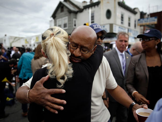 Philadelphia Mayor Michael Nutter, center right, hugs Lori Dee Patterson, a nearby resident, after she handed him a cup of coffee after he spoke at a news conference near the scene of a deadly train derailment, Wednesday in Philadelphia.