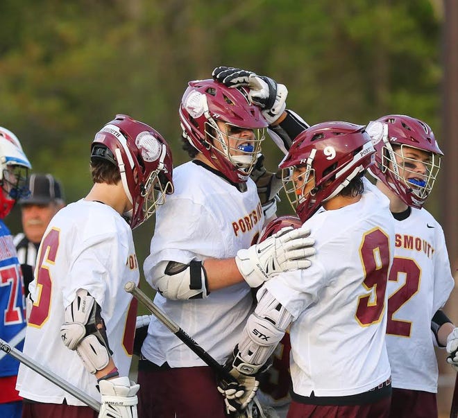 Members of the Portsmouth High School boys lacrosse team congratulate John Franks, center, after scoring a goal early in the second quarter of Friday's Division II game against Winnacunnet. Matt Parker/Seacoastonline
