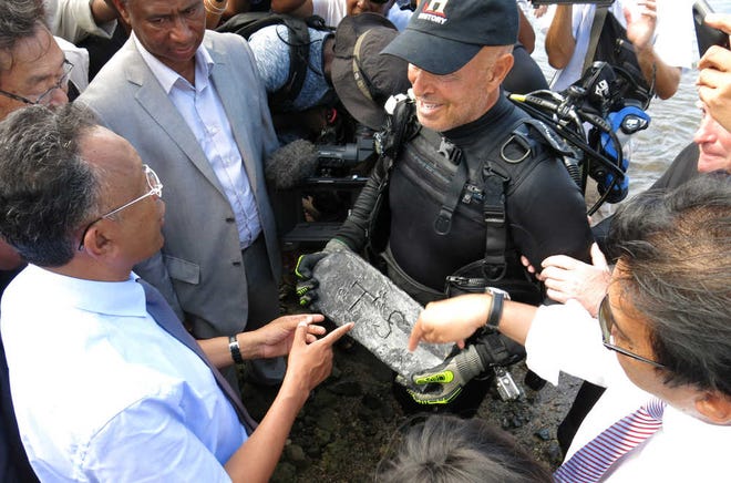 In this photo taken Thursday, May, 7, 2015 underwater explorer Barry Clifford, right, presents a silver bar he believes is part of the treasure of the pirate Captain Kidd, to the president of Madagascar, Hery Rajaonarimampianina, left, on Sainte Marie Island, Madagascar. (AP Photo/Martin Vogl)