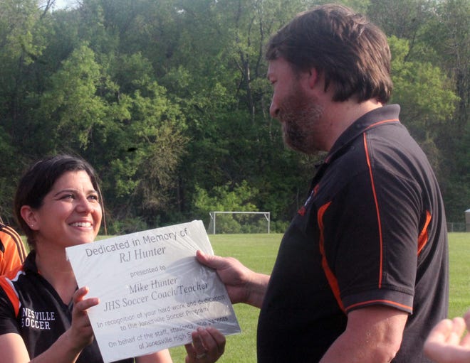 Jonesville girls soccer coach Olivia Varney presents Mike Hunter with commemorative plates honoring Hunter's uncle, R.J., that will adorn the shelters at the Comets' soccer facility. Hunter made a donation in his uncle's name that helped build the shelters. DAVID VANTRESS PHOTO