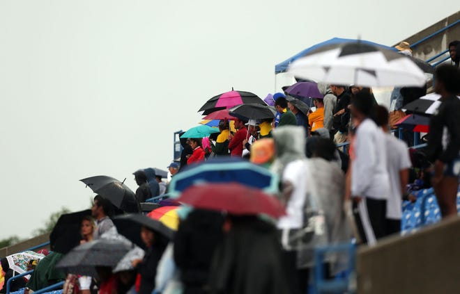 Fans and teammates shade themselves from the rain using umbrellas as they watch the action on the track at the NJCAA Track and Field Championships at Gowans Stadium in Hutchinson on Saturday.