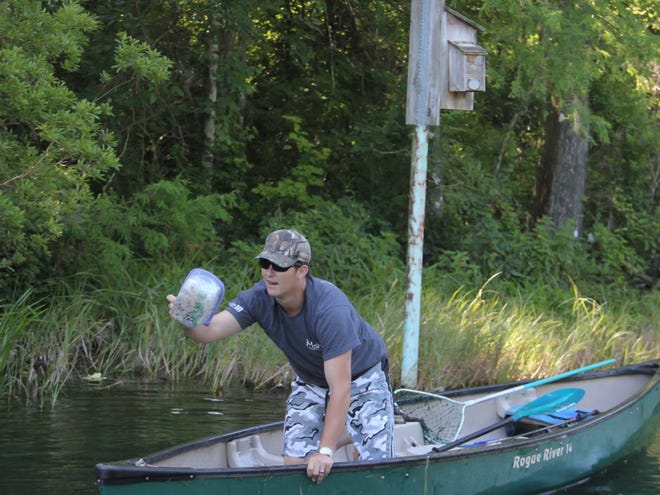 Randy Dorsey shows off a container filled with salad and a vinaigrette dressing that he removed from the water at the annual Rainbow River Spring Clean-up on Saturday, May 16, 2015 in Dunnellon, Fla. Volunteers boated, snorkeled and kayaked through the Rainbow River removing trash and debris.