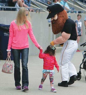 Photo by Jake West/New Jersey Herald Tara Salzman holds hands with her daughter, Juliana Salzman, as she looks back curiously at mascot Herbie the Miner, during the Sussex County Miners exhibition game at Skylands Stadium on Saturday in Frankford.