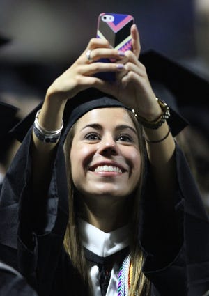 Emily Kjellman, who earned a degree in elementary and special education, takes a photo as PC's graduates file into the Dunkin' Donuts Center on Sunday. The Providence Journal/Glenn Osmundson