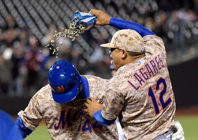 New York Mets' Juan Lagares (12) celebrates with John Mayberry Jr. after Mayberry hit an infield single to drive in the winning run as the Mets defeated the St. Louis Cardinals, 2-1, in the 14th inning of a baseball game Monday, May 18, 2015, at Citi Field in New York.