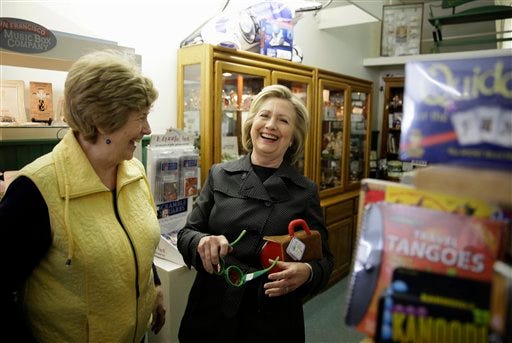 Democratic presidential candidate Hillary Rodham Clinton laughs with Laree Randall, owner of Laree's gift shop, as she looks at toys Tuesday, May 19, 2015, in Independence, Iowa. (AP Photo/Charlie Neibergall)