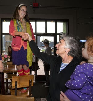 Eileen Nittler stands on a chair and is congratulated on being elected to the Eugene School Board by school board member Mary Walston (right), who holds Sienna Hove, during a celebratory party at Hop Valley Brewing in Eugene on Tuesday. Walston was re-elected to the board. (Andy Nelson/The Register-Guard)
