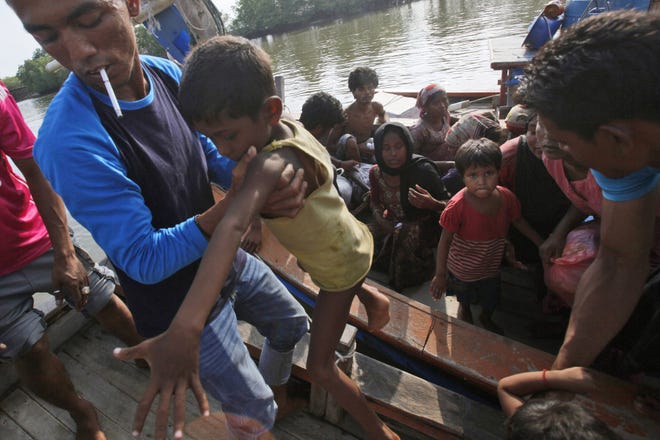An fisherman lifts a boy off a boat full of rescued migrants in Simpang Tiga, Aceh province, Indonesia, Wednesday. The Associated Press