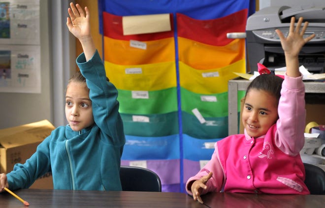 Charlton Street Elementary School first-graders Naomys Carrero-Soto, 6, left, and Jonelys Arroyo, 7, raise hands to answer a question during an English Language Learner class in Southbridge. T&G Staff/ Paul Kapteyn