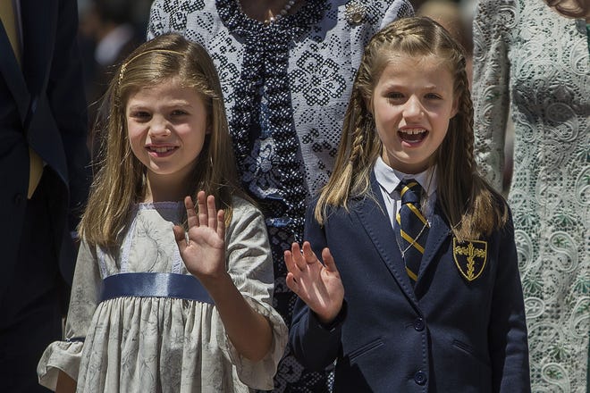 Princess Sofia, left, and Crown Princess Leonor, right, wave as they pose for a picture during Princess Leonor's first communion in Madrid, Spain. THE ASSOCIATED PRESS