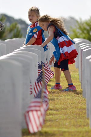 Hundreds of volunteers placed flags at the foot of grave markers at Jacksonville National Cemetery during its Memorial Day Observance on Saturday, May 23, 2015.