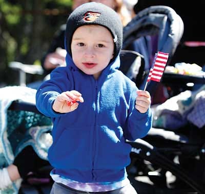 Photo by Kimberly Jones/New Jersey Herald - Calvin Pakutka, 3, of Hopatcong, picks up candy and waves his flag at the Memorial Day Parade in Hopatcong on Saturday.
