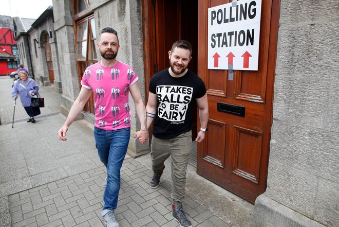 Partners Adrian, centre left and Shane, leave a polling station after casting their vote in Drogheda, Ireland, Friday.