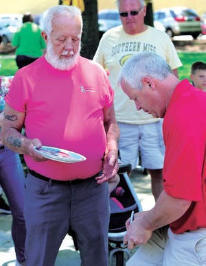 Dan Warther signs the No. 1 wooden plate for the winning bidder, Bill Zeigler of Midvale, with the bid of $3,600 Saturday at the Canal Dover Festival.