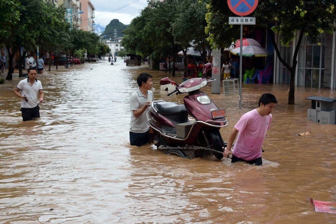 Residents haul a motorcycle through a flooded street in China's Guangxi 
Zhuang Autonomous Region last week. Dozens of people have been killed and 
several are missing in flooding in China.AP PHOTO / ZHOU HUA