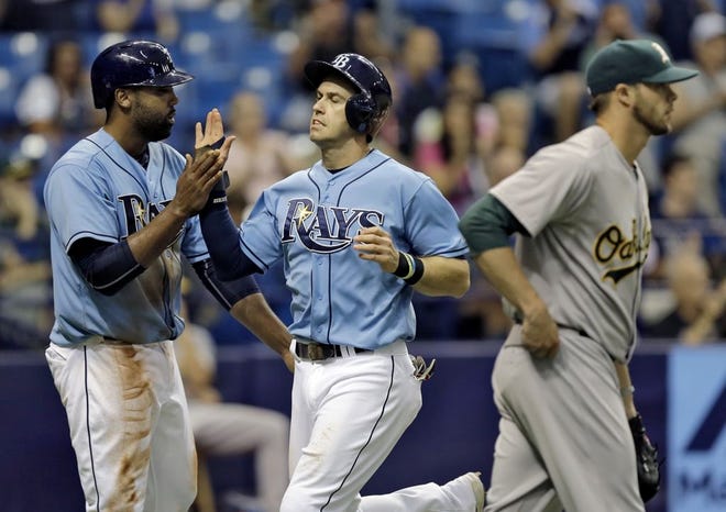 The Tampa Bay Rays' Evan Longoria, center, celebrates with Joey Butler, left, after scoring on a two-run single by Logan Forsythe off Oakland Athletics relief pitcher Evan Scribner, right, during the eighth inning on Sunday in St. Petersburg.