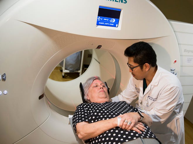 In this photo taken May 19, 2015, Judith Chase Gilbert, of Arlington, Va., is loaded into a PET scanner by Nuclear Medicine Technologist J.R. Aguilar at Georgetown University Hospital in Washington. Gilbert shows no signs of memory problems but volunteered for a new kind of scan as part of a study peeking into healthy brains to check for clues about Alzheimer's disease.