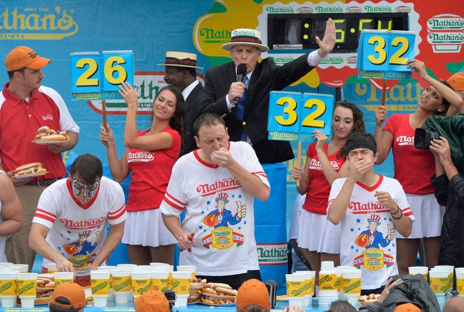 Nathan's July 4th Hot Dog eating contest.

The 99th annual Nathan's July 4th hot dog eating contest, 2014, in Coney Island was a soaker. Despite the heavy rainfall from hurricane Arthur, the contest went on.

Defending champ Joey Chesnut (Center) won with 61 hot dogs and buns in 10 minutes while women crowned new champion Miki Sudo, with 34 hot dogs and buns. The defending women champ Sonya "The Black widow" Thomas finished 2nd with 27 3/4 hot dogs and buns.

Champ Joey Chesnut proposed to his girlfriend Neslie Ricasa on live TV ,(who is also eating competitor).

(Photo contributed)