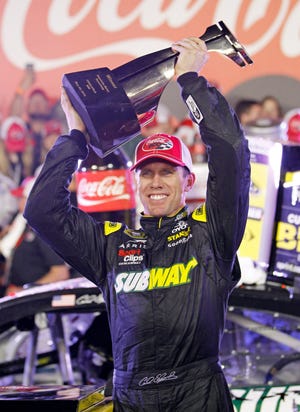 Carl Edwards raises the trophy in Victory Lane Sunday after winning the NASCAR Sprint Cup series race at Charlotte Motor Speedway in Concord, N.C. THE ASSOCIATED PRESS