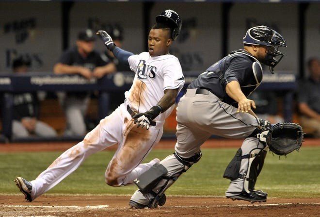 Tampa Bay's Tim Beckham, left,  scores on Jake Elmore's single as Seattle Mariners catcher Welington Castillo waits for the throw during the third inning.