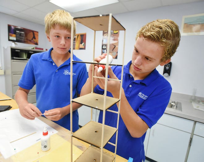 Christopher Loffler, right, and Frankie Muldowney, glue together pieces for an earthquake proof structure during class on Wednesday at the STEMM Academy in Valparaiso. The school will be graduating the first group of students who have attended class for all three years of middle school.