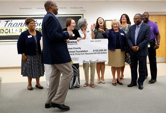 Judy Boles, executive director of The Education Foundation of Alachua County, at right of the big check, requests the real check from Dollar General Distribution Center Alachua Manager Alain Arrendell at Mebane Middle School in Alachua Wednesday, May 27, 2015.