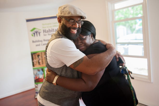 New homeowner Lonnie Baldwin (left) hugs his wife's best friend, Valerie McNear, of Mount Holly, Thursday while showing her the Mount Holly house that he will own with the assistance of Habitat for Humanity.