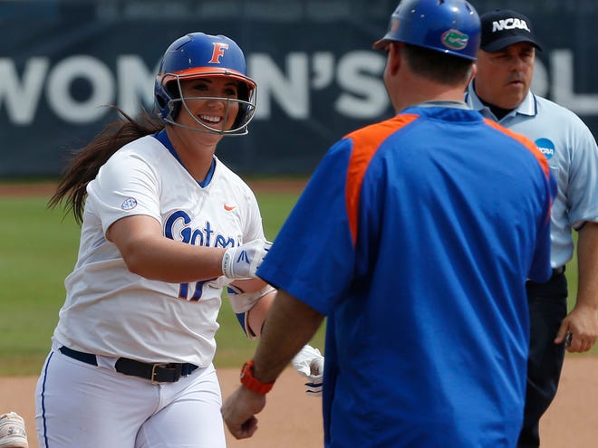 Florida's Lauren Haeger, left, is congratulated by head coach Tim Walton after hitting a home run in the first inning of a game against Tennessee in the NCAA Women's College World Series softball tournament in Oklahoma City on Thursday.