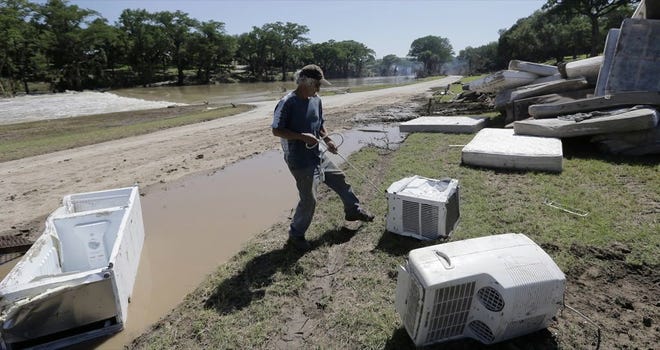 JOHNNY RODRIGUEZ works to salvage appliances from homes destroyed by flooding along the Blanco River on Friday in Wimberley, Texas.