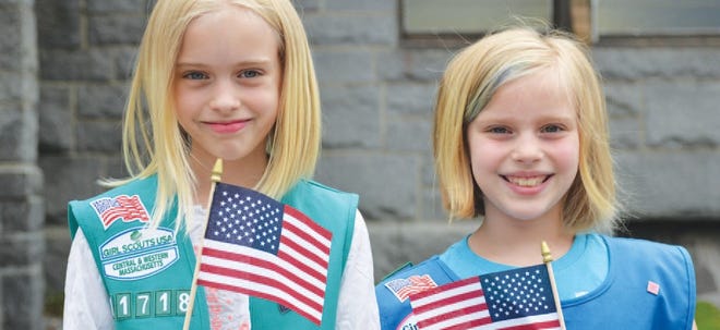 Girl Scouts and sisters Sully, left, and Caseigh McDonough hold American flags before the Memorial Day ceremony at Evergreen Cemetery.