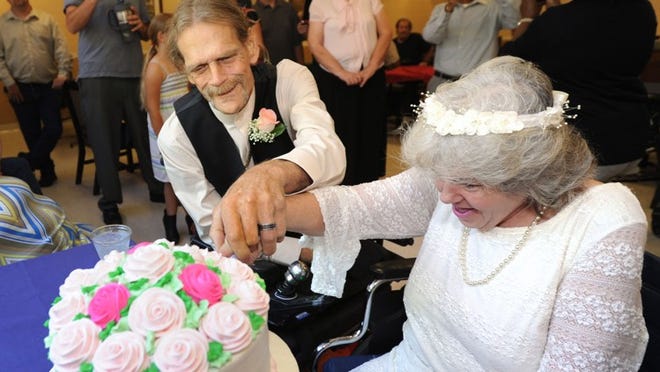 Debbie Rivera, 54, and John Whaley, 58, cut their cake surrounded by friends and family after their wedding ceremony in Green Cove Springs, Fla. on Saturday, May 23, 2015. Rivera and Whaley met while patients receiving hospice care and decided they wanted to be together for the rest of whatever time they have. The bride and groom are both chronic obstructive pulmonary disease patients, and the groom is a triple amputee, missing both legs and a hand due to his illness. (Bob Mack/The Florida Times-Union via AP)