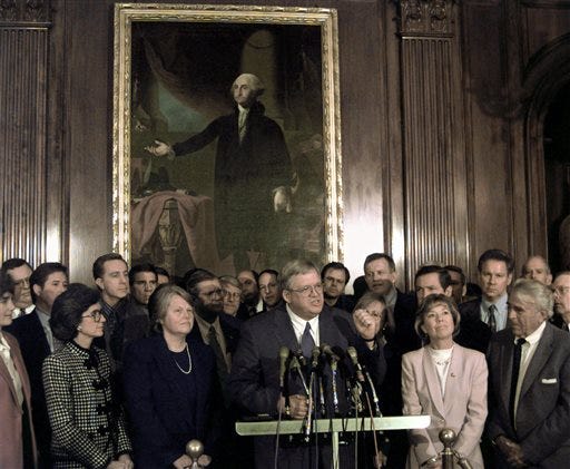 In this Jan. 5, 1999 file photo, under a portrait of George Washington, Rep. Dennis Hastert, R-Ill., accompanied by wife Jean, next to him left, and fellow Republicans, meets reporters on Capitol Hill after being nominated by House Republicans to become the next House speaker. A newly unveiled indictment against Hastert released Thursday, May 28, 2015, accuses the Republican of agreeing to pay $3.5 million in hush money to keep a person from the town where he was a longtime schoolteacher silent about "prior misconduct." (AP Photo/Greg Gibson, File)