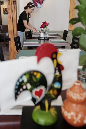 Jessica Coelho, owner of Tia Maria's European Cafe, sets up a table at her restaurant on North Water Street in New Bedford.  PETER PEREIRA/THE STANDARD-TIMES