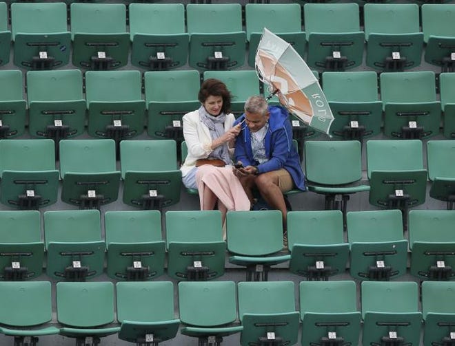 The wind pulls at the umbrella of a spectator as weather conditions suspended the fourth round match between France's Alize Cornet and Ukraine's Elina Svitolina at the French Open tennis tournament at Roland Garros stadium, in Paris, France, Sunday, May 31, 2015.
