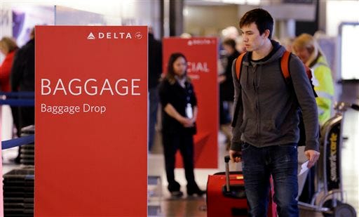 In this photo taken Tuesday, March 24, 2015, travelers walk toward the baggage drop area for Delta airlines at Seattle-Tacoma International Airport in SeaTac, Wash. This summer travel season, Delta plans to preload carry-on bags above passengers' seats on some flights. (AP Photo/Elaine Thompson)