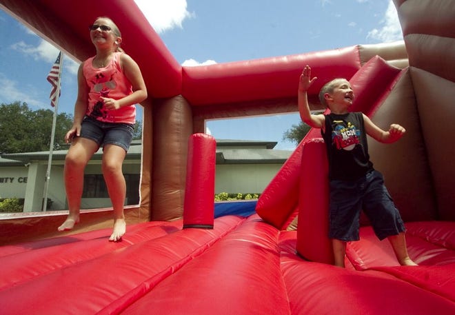 Emilie Huggins , 9, left, and her brother Jaxon Huggins, 5, enjoy the bounce house Saturday during the Dundee Library Summer Reading Program Kickoff Carnival at the Dundee Community Center.