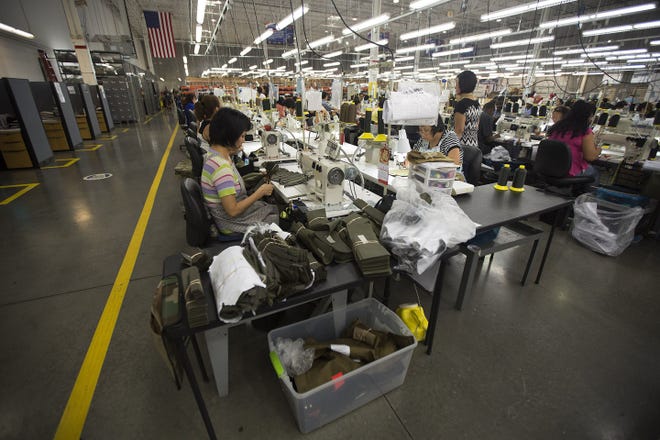 Workers assemble body armor in the sewing area in the Point Blank Body Armor factory in Pompano Beach, Fla. The Associated Press